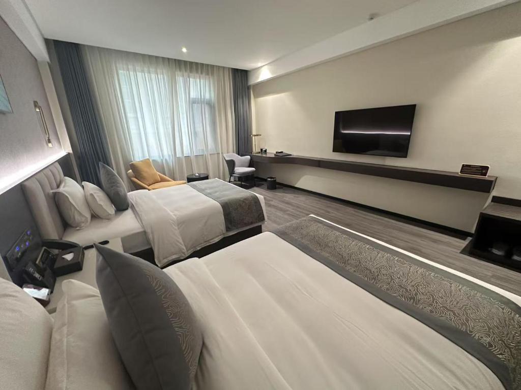 a hotel room with two beds and a flat screen tv at 巴域永源酒店 in Phumĭ Bavĕt (2)