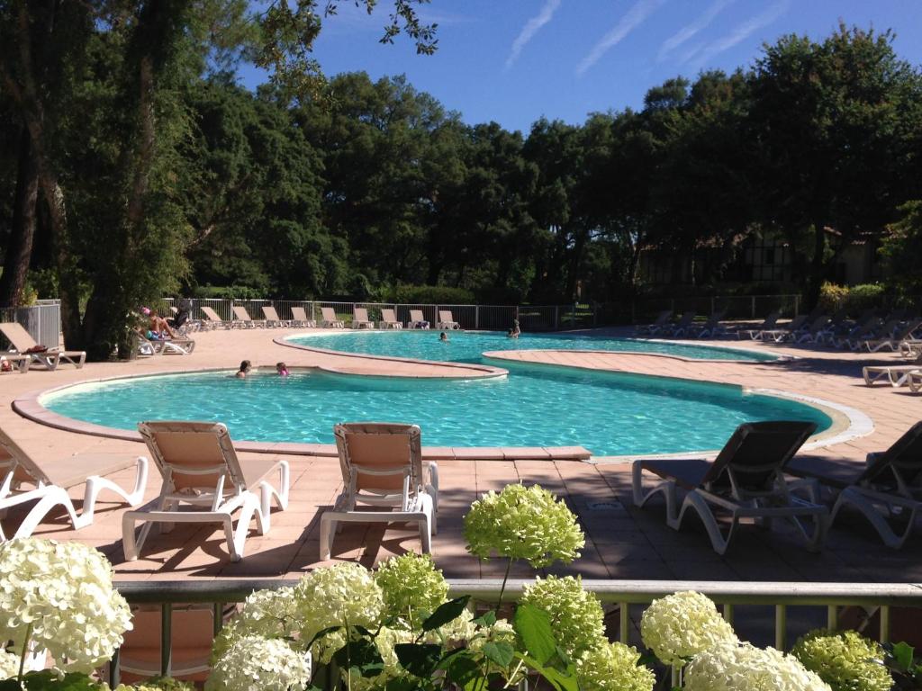 - une piscine avec des chaises et des personnes dans l'eau dans l'établissement M-Golf 01-Moliets Maisonnette pour 6 personnes dans résidence avec piscine, à Moliets-et-Maa