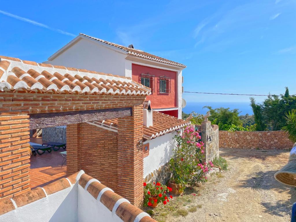 a brick house with a red window and flowers at Villa Francisca in Málaga