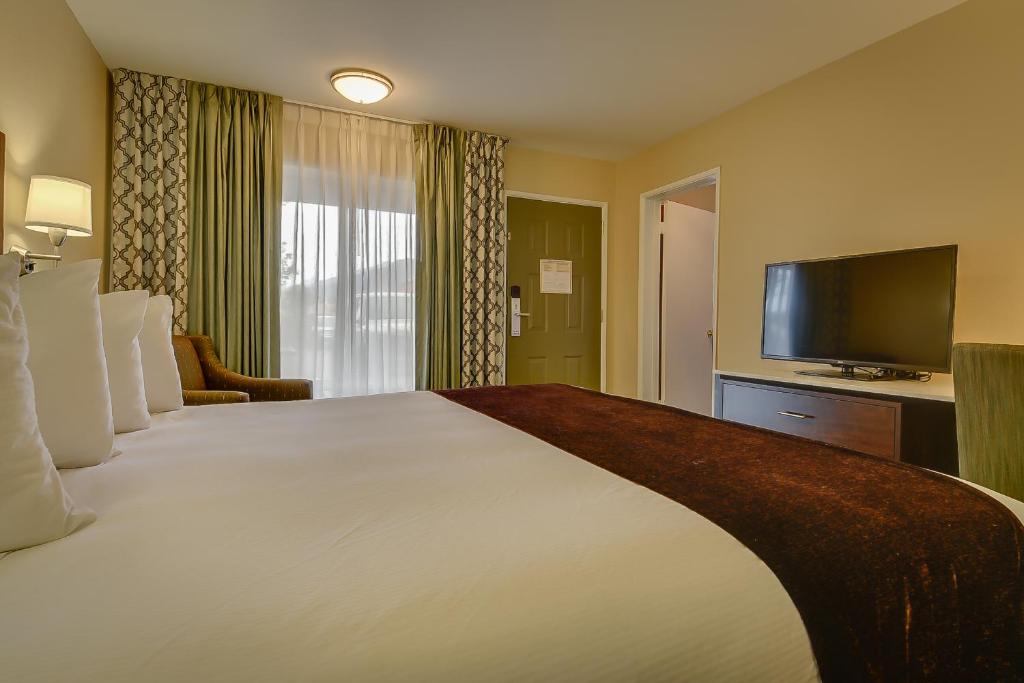 a hotel room with a large bed and a flat screen tv at Vagabond Inn Bishop in Bishop