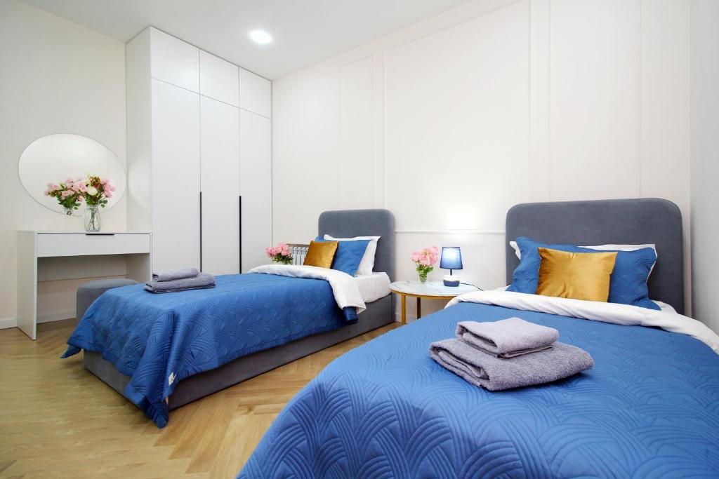 two beds in a bedroom with blue and yellow pillows at Central Light Apartment in Almaty