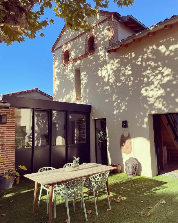 un patio avec une table et des chaises devant une maison dans l'établissement Nuit romantique avec jacuzzi privé !, à Noé