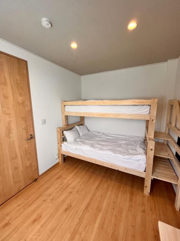 a bedroom with two bunk beds and a wooden floor at hotel kusanagi in Nanao