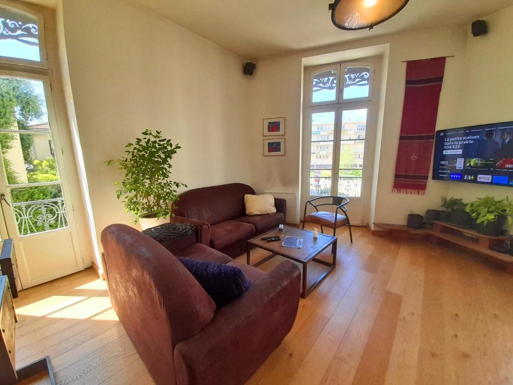 un salon avec deux canapés et une télévision à écran plat dans l'établissement L'Oasis Lumière - T3 central, fibre, TV connectée, à Montpellier