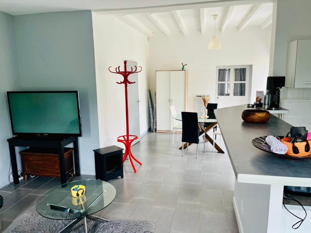 a living room with a flat screen tv and a table at Maison entre Saumur et Montreuil Bellay La Motte in Artannes-sur-Thouet