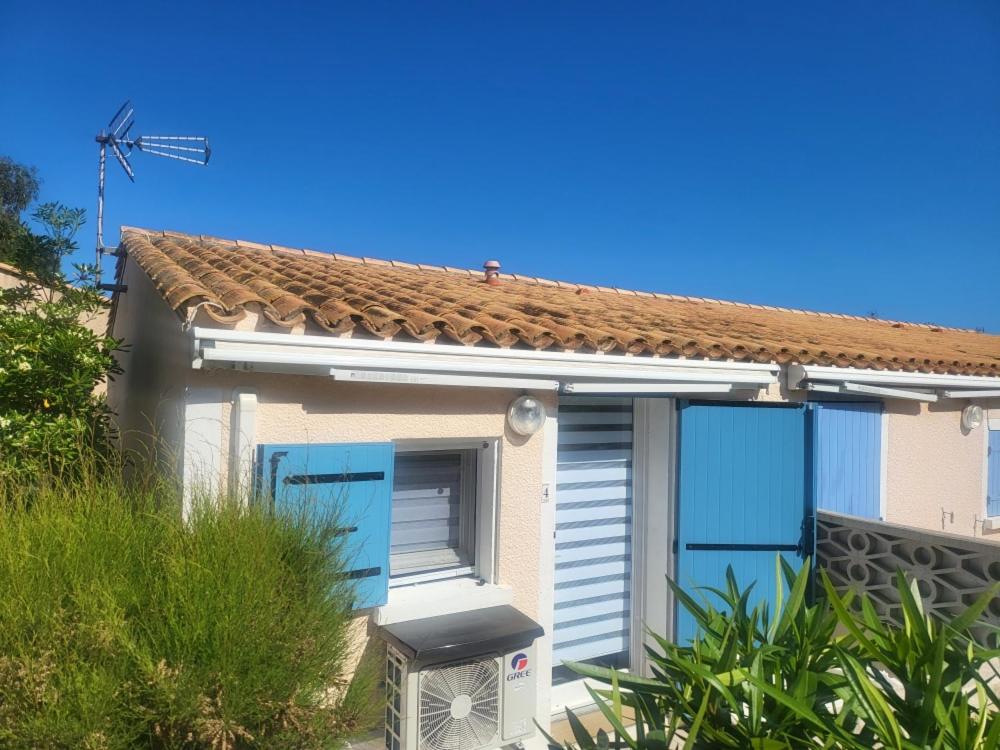 une petite maison avec des portes bleues et un moulin à vent dans l'établissement loue Maison plein pied barcares 28 m2, au Barcarès
