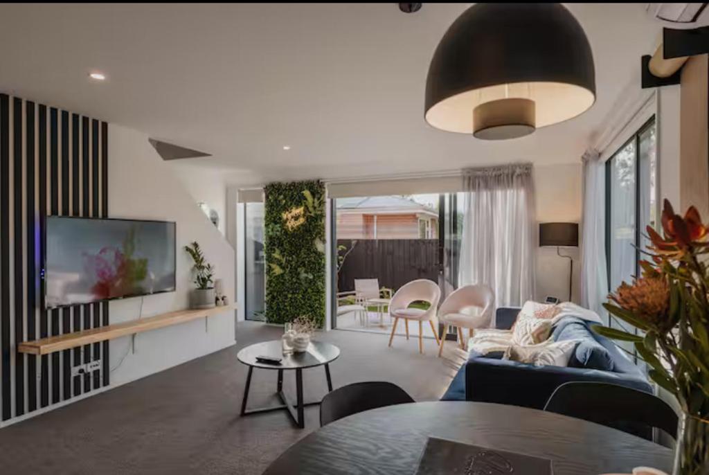 a living room with a blue couch and a tv at Travellers' dream steps from shops and close to Airport in Christchurch