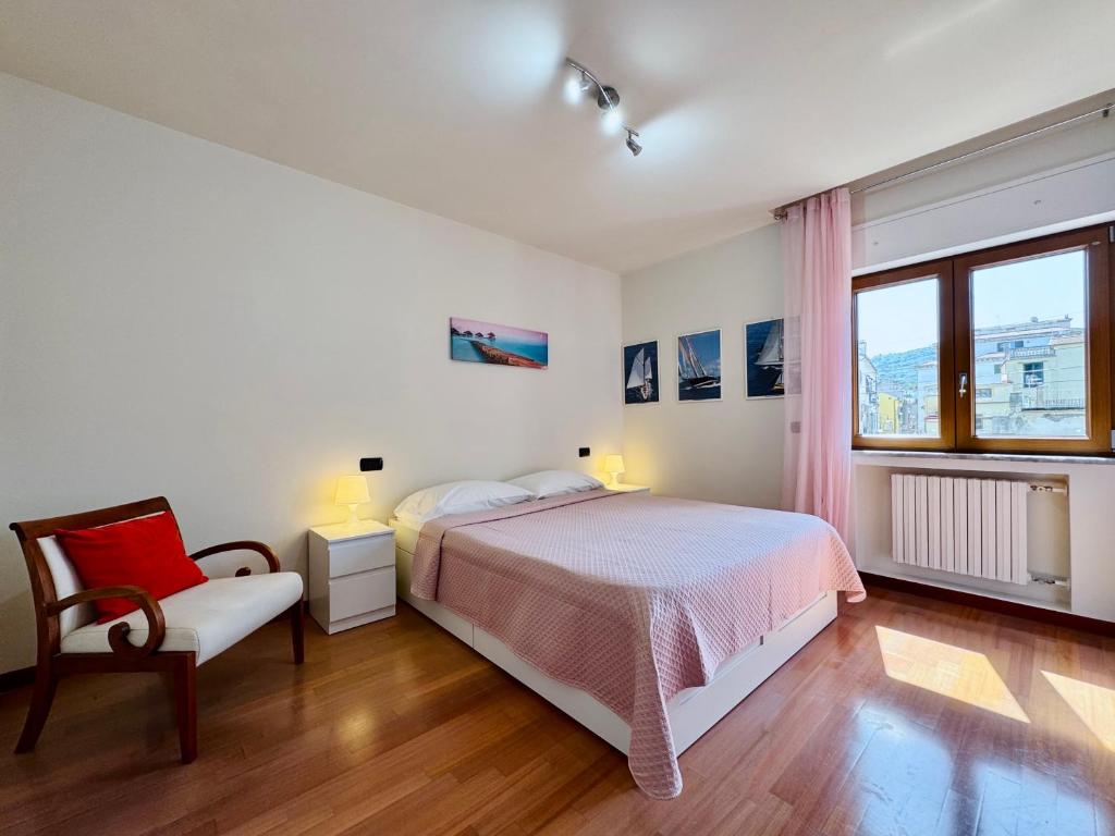 YourHome - A Casa di Manuela في سانتّانييلّو: غرفة نوم بها سرير وكرسي ونافذة