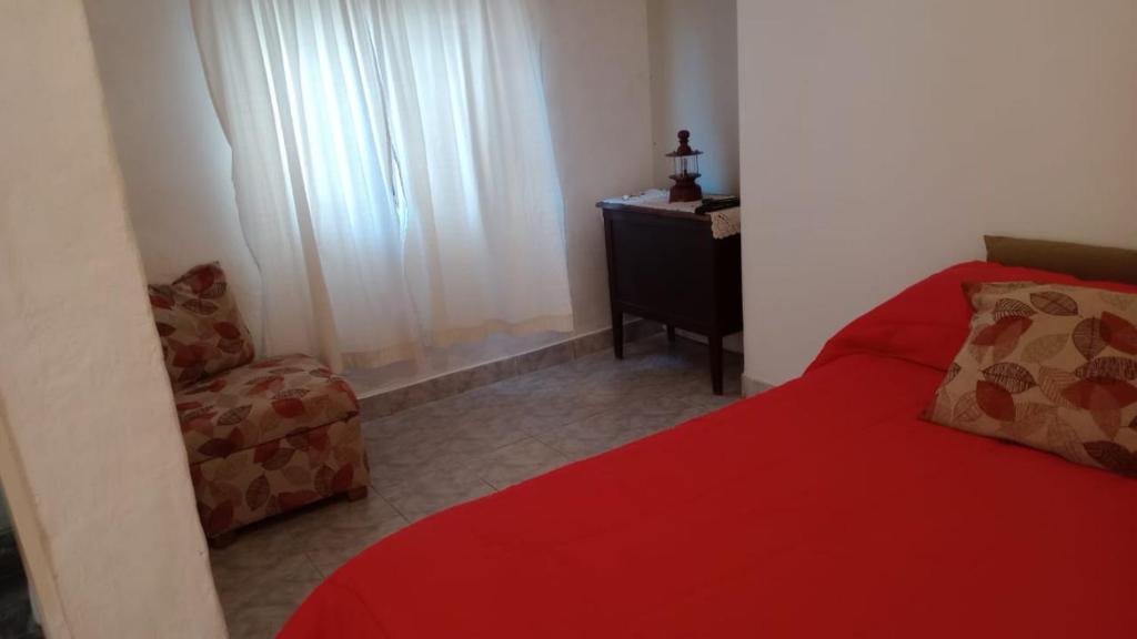 a bedroom with a red bed and a chair at El depto de Esther 2 in Tandil