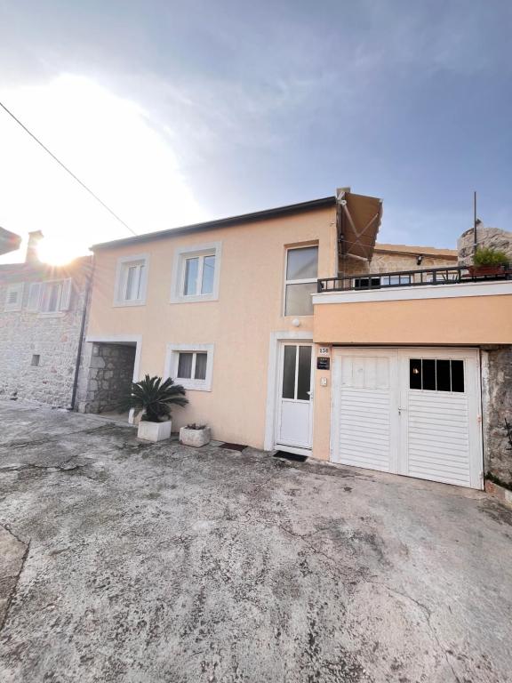 a house with two white garage doors and a driveway at Lavanda Apartment in Stari Grad