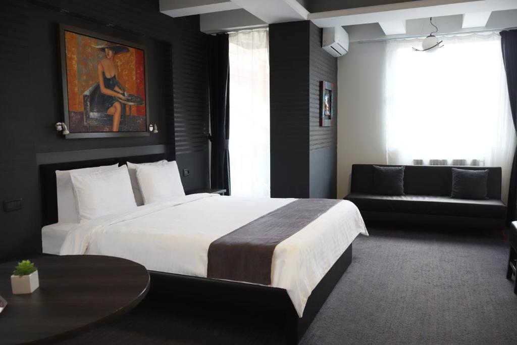 a bedroom with a large white bed and a couch at Sienna Apartments in Skopje