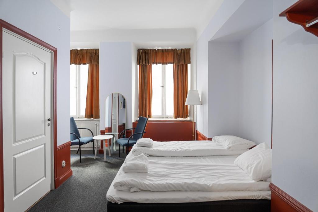 a hotel room with two beds and a table and chairs at Hotell Skeppsbron in Stockholm