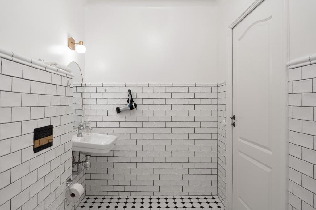 a white tiled bathroom with a sink and a toilet at Hotell Skeppsbron in Stockholm