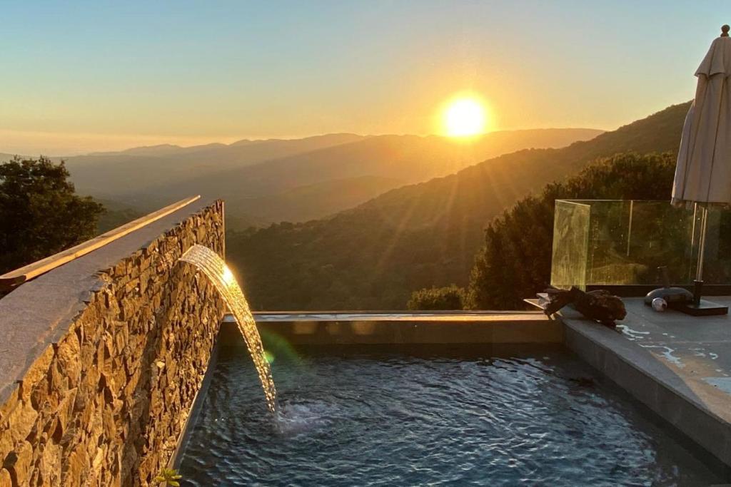 une piscine avec un coucher de soleil en arrière-plan dans l'établissement Villa climatisée vue mer piscine privée chauffée wifi 810 personnes, à Sollacaro