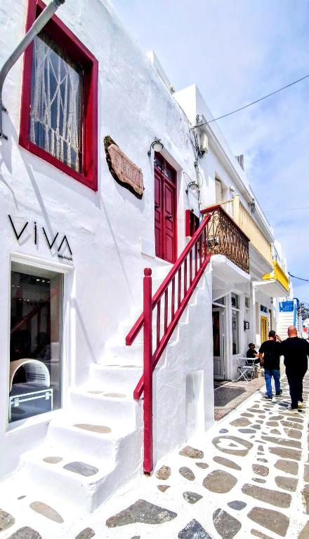 a white building with red doors and stairs on a street at SIKATE Hospitality in Mikonos