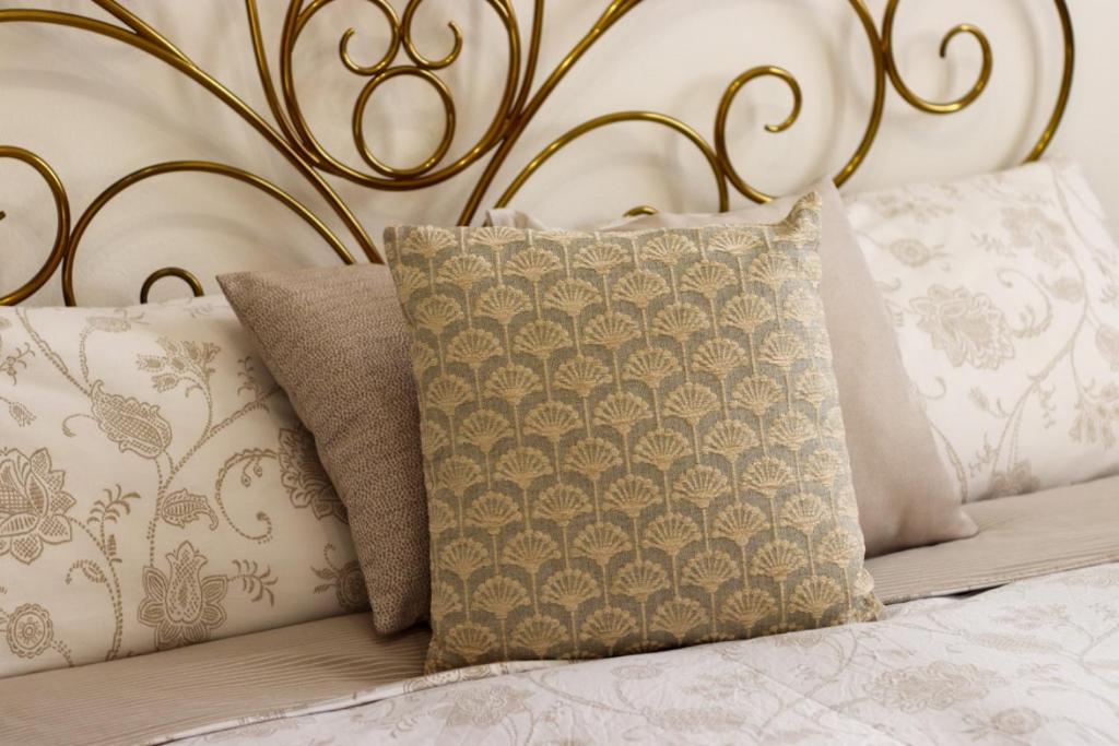 - un lit avec des oreillers blancs et une tête de lit dorée dans l'établissement Dimore Al Borgo, à Montagnana