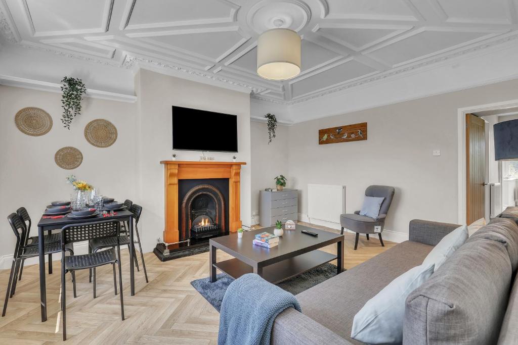 een woonkamer met een bank, een tafel en een open haard bij Cozy 2 Bedroom Cottage in West Woodburn