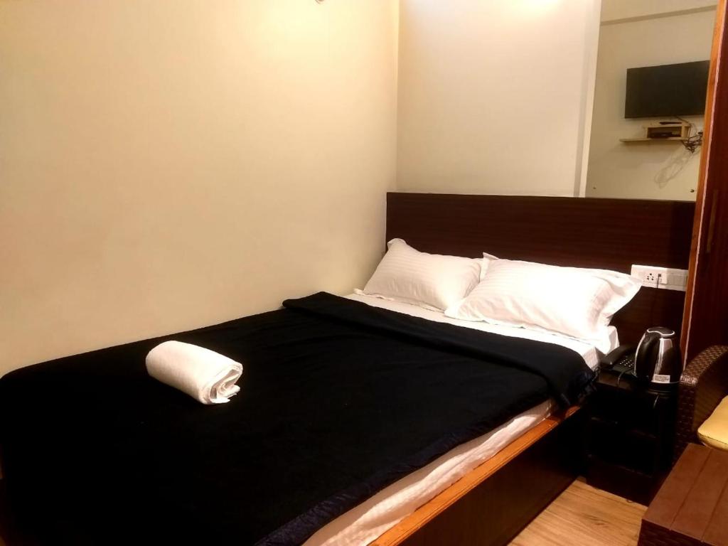 a small bedroom with a black bed with white pillows at Shillong Rains Inn in Shillong