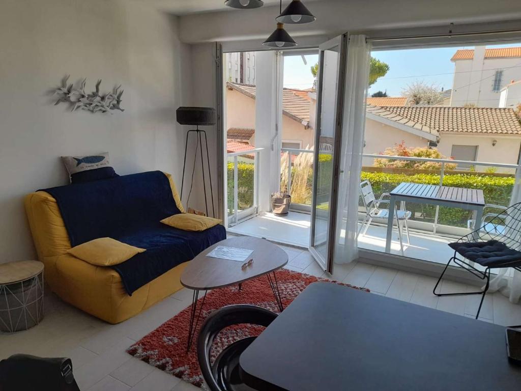 un salon avec un canapé et une table dans l'établissement Appartement T2 à 300m du marché - Balcon, cuisine équipée, chambre confort, idéal vacances. - FR-1-494-183, à Royan