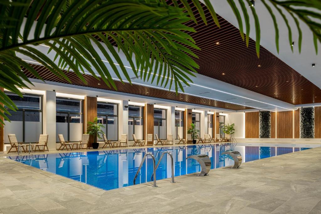 a swimming pool with chairs and tables in a building at Hotel Alexandrion Experience in Sinaia