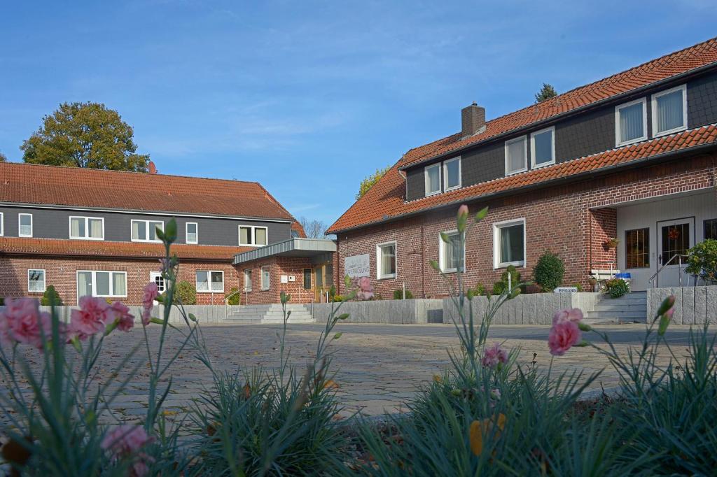 a row of brick houses with flowers in a courtyard at Hotel Zur Erholung & Restaurant Amme's Landhaus in Eicklingen