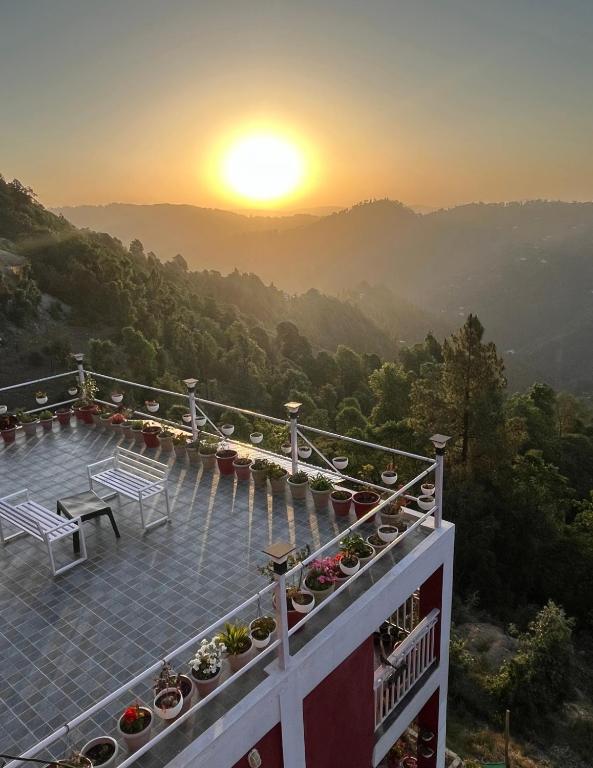 a balcony with a view of the mountains at sunset at EcoEscape Mukteshwar in Mukteshwar