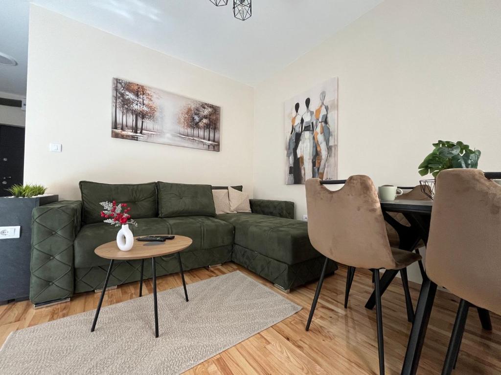 Una sala de estar con un sofá verde y una mesa. en Apartman LuJ Zlatibor, en Zlatibor