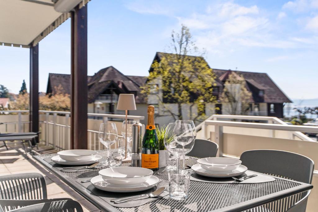 a table with glasses and wine bottles on a balcony at STAYS Hafenblick direkt am See in Hagnau