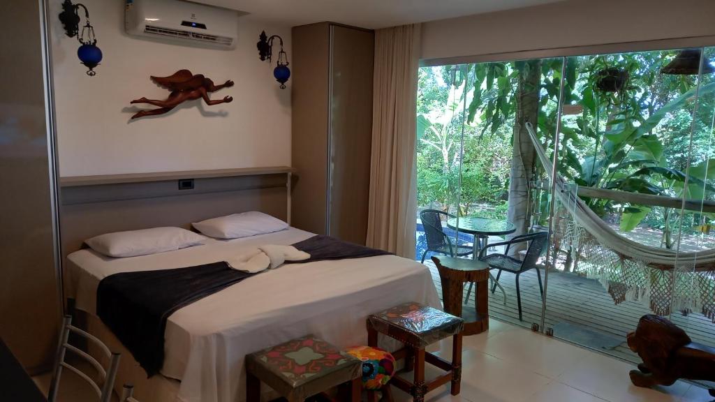a bedroom with a bed and a large window at Bangalô no alto da colina no Villas do Pratagy - Maceió in Maceió