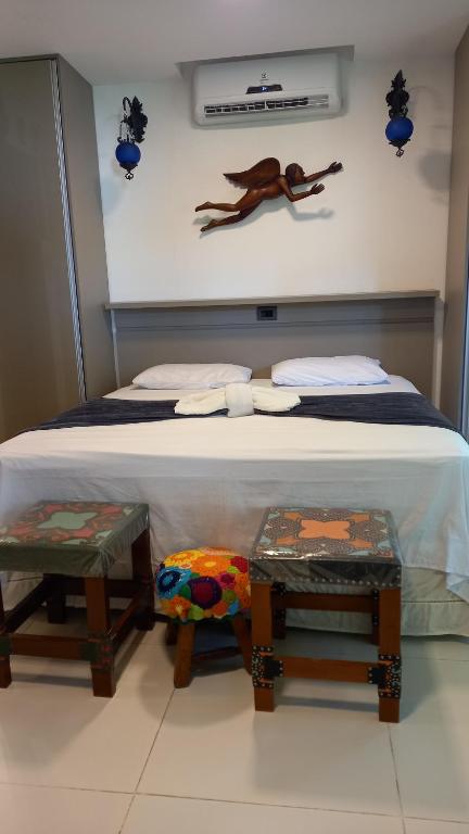 a bedroom with a bed with two stools next to it at Bangalô no alto da colina no Villas do Pratagy - Maceió in Maceió