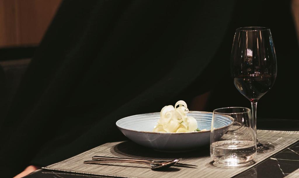 una ciotola di cibo su un tavolo accanto a un bicchiere di vino di The Blackpine Hotel - Small Luxury Hotels a Escaldes-Engordany