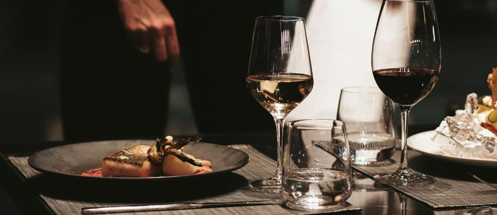 un tavolo con un piatto di cibo e due bicchieri di vino di The Blackpine Hotel - Small Luxury Hotels a Escaldes-Engordany