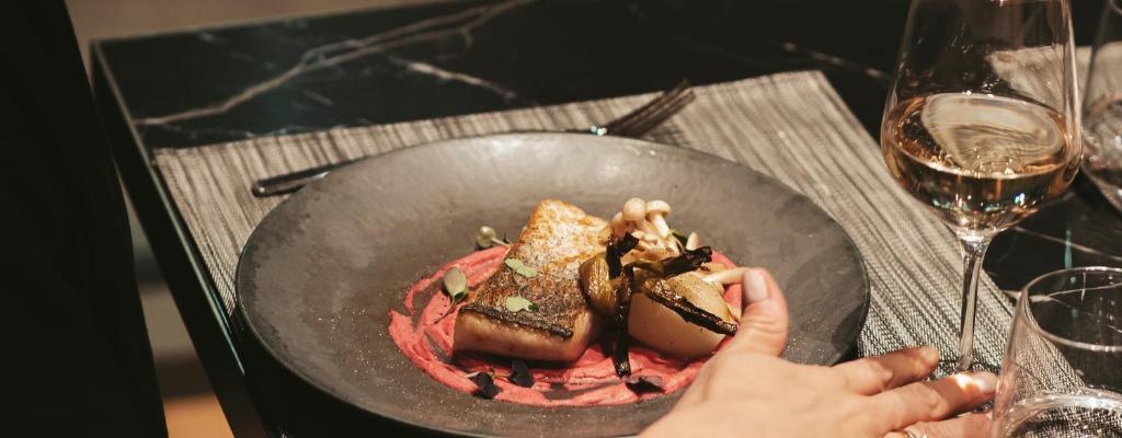 una persona che tiene un piatto di cibo in un wok di The Blackpine Hotel - Small Luxury Hotels a Escaldes-Engordany
