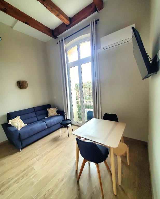 un salon avec un canapé bleu et une table dans l'établissement Bioves - Mezzanine studio, Charming & Comfortable, à Menton
