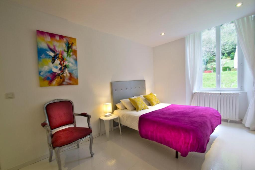 a bedroom with a bed with a purple blanket and a chair at Maison La Douane - Comprends nettoyage professionnel et le linge in Laruns