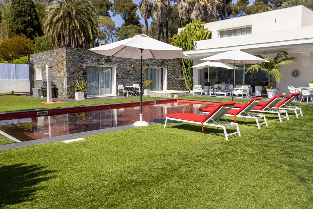 - un groupe de chaises longues et de parasols à côté de la piscine dans l'établissement Villa Deluxe Antibes & Private Appartement - Pool - Spa - Cinéma, à Antibes
