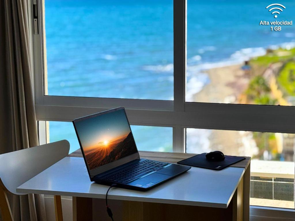 un ordenador portátil sentado en un escritorio frente a una ventana en Beachfront Studio ,The View Calahonda, Panoramic Sea Views, en Mijas Costa