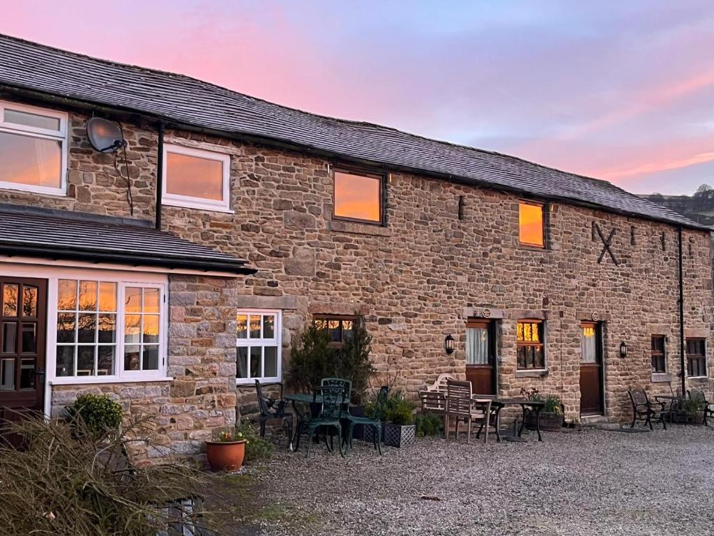 a stone house with tables and chairs in front of it at Riding house Farm Cottages in Castleton
