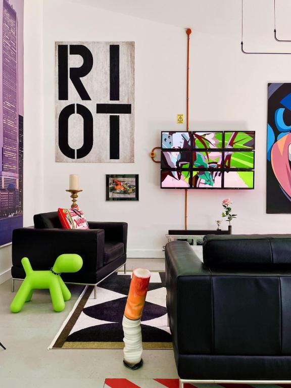 un salon avec des meubles noirs et des œuvres d'art au mur dans l'établissement Le Loft des Cévennes, à Ganges