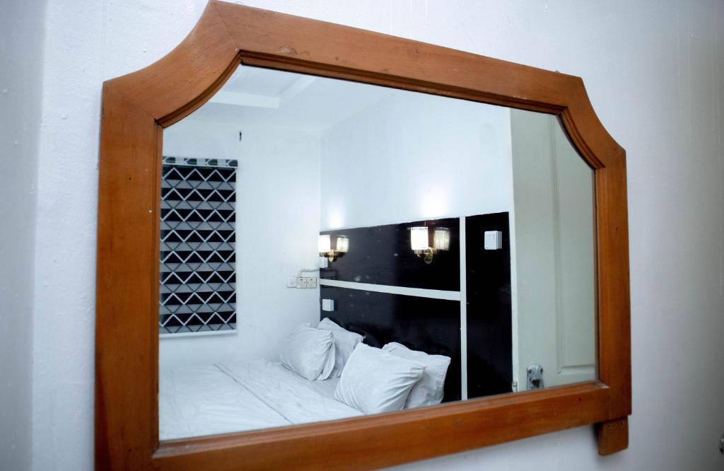 einen Spiegel an der Wand mit einem Bett in einem Zimmer in der Unterkunft Option one hotel and suite in Benin-Stadt