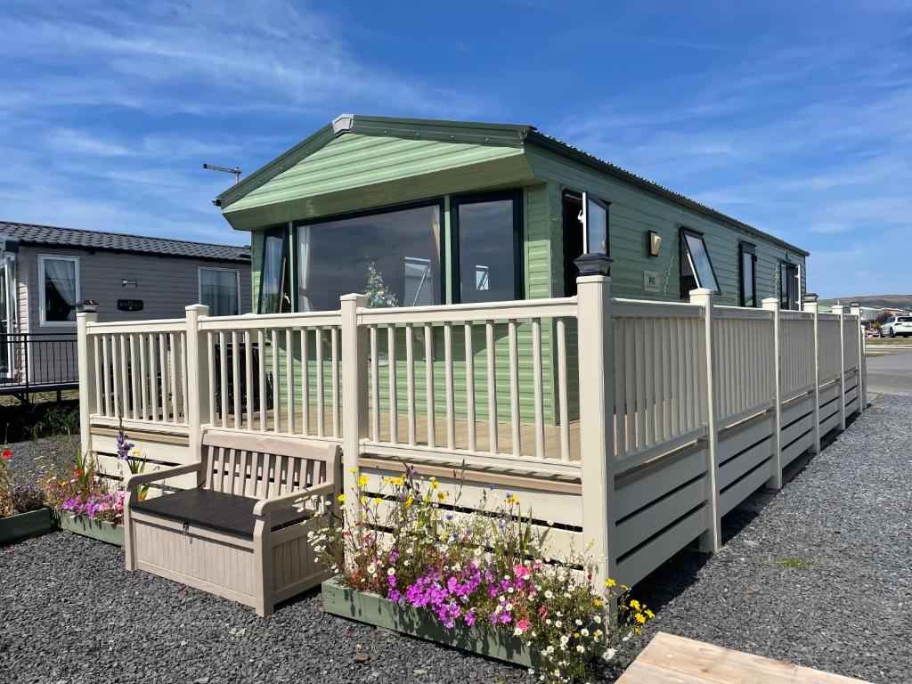a small house with a white fence and flowers at Cambrian Rio Caravan in Ynys-lâs Station