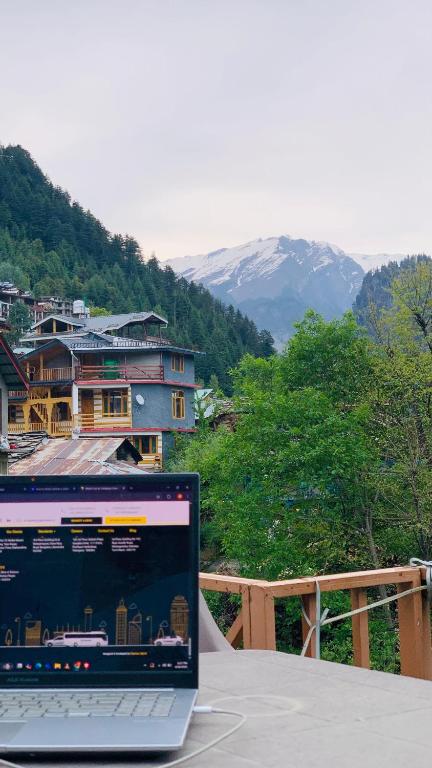 un computer portatile seduto su un tavolo con vista su una montagna di Hostello Manali a Manāli