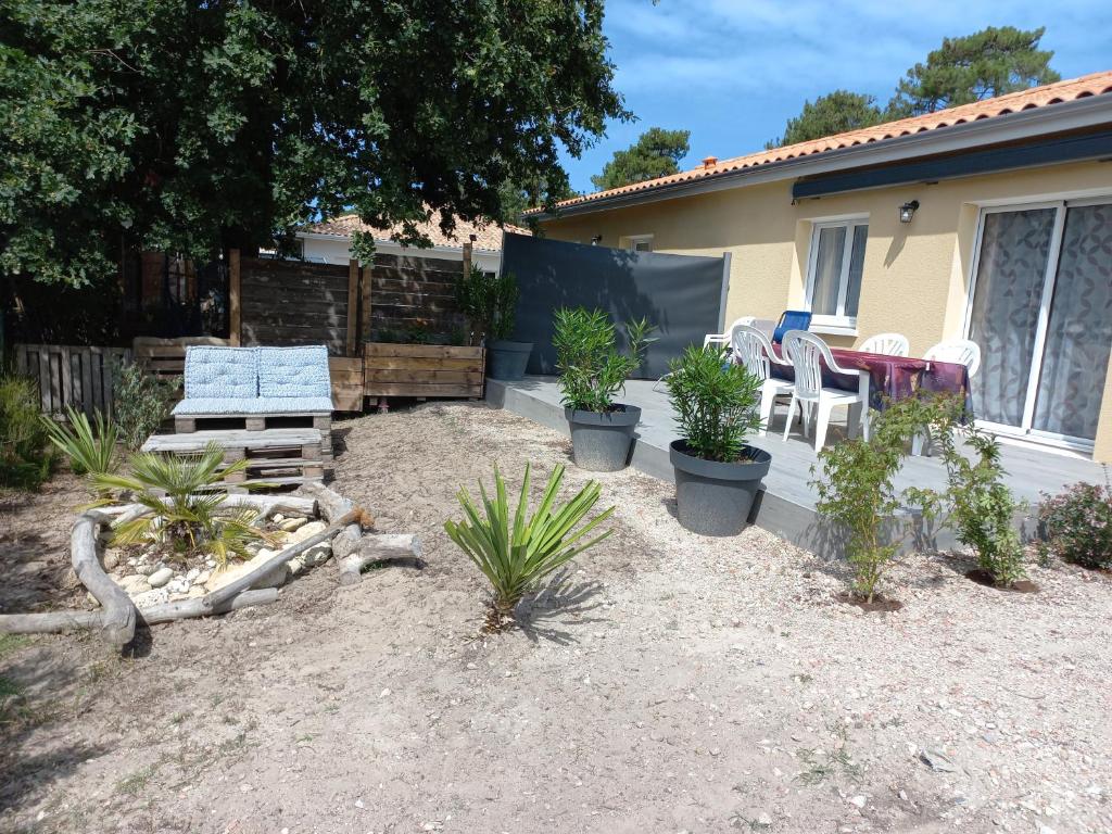 une terrasse avec des chaises et des plantes devant une maison dans l'établissement CAP MONTA - Maison Neuve, à Montalivet-les-Bains