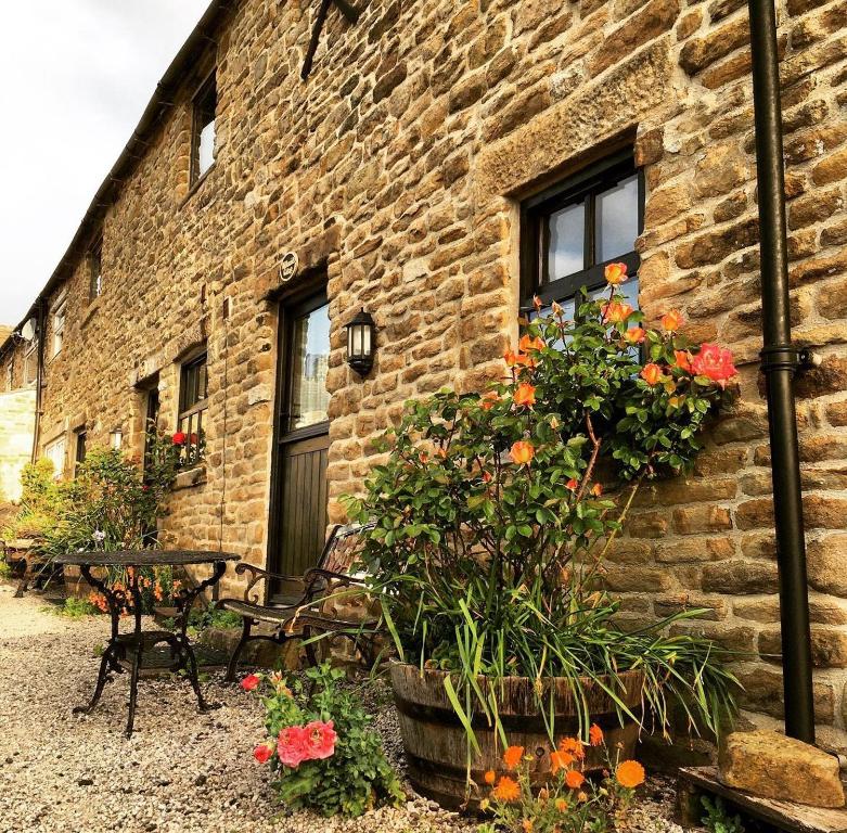 a brick building with flowers in front of it at Riding house Farm Cottages in Castleton