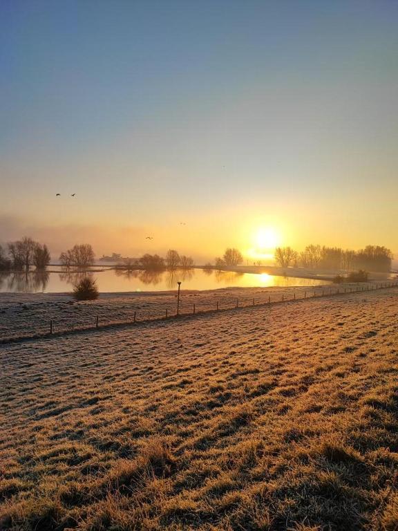 ein frostiges Feld mit einem Zaun davor, ein Sonnenuntergang in der Unterkunft Parva Domus in Xanten