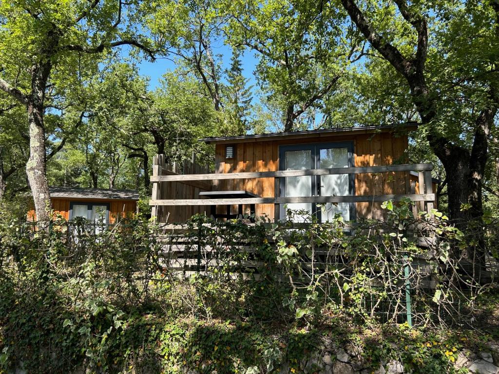 une maison dans les bois avec une clôture dans l'établissement Camping Les Cent Chênes, à Saint-Jeannet