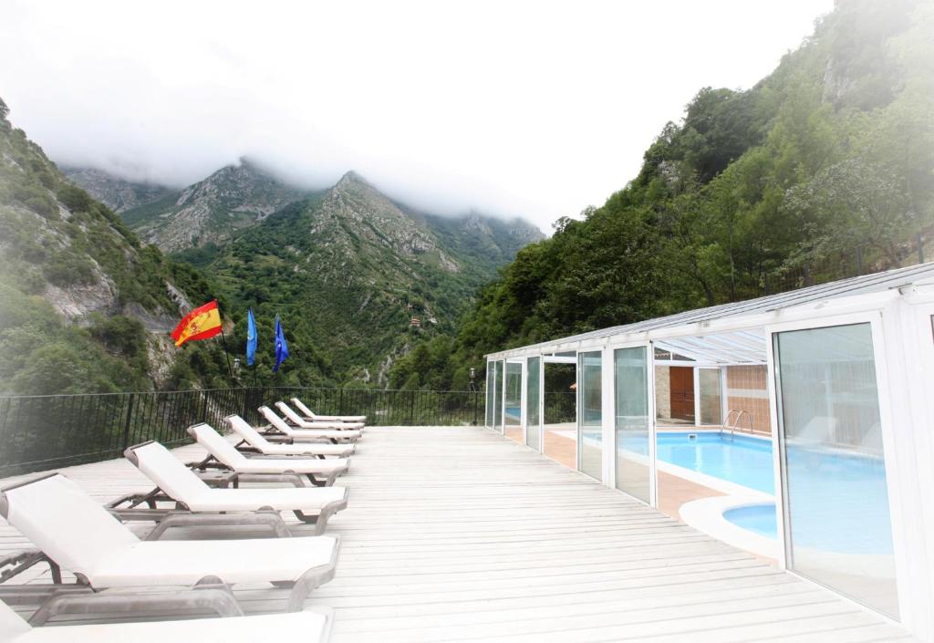 una fila di sedie a sdraio accanto alla piscina di Hotel Puente Vidosa ad Amieva