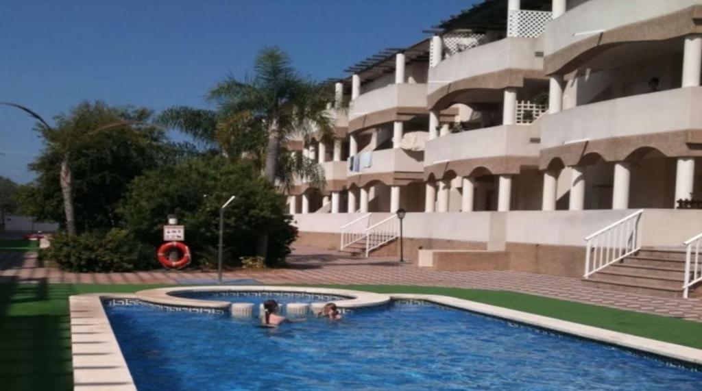 zwei Personen in einem Pool vor einem Gebäude in der Unterkunft 3 BEDROOM LUXURY PENTHOUSE, BEACH, POOL, and GOLF, WIFI, Large TV SATELLITE,GARAGE in Vinarós