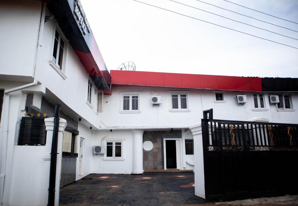 ein weißes Gebäude mit einem roten Dach und einem Tor in der Unterkunft Option one hotel and suite in Benin-Stadt