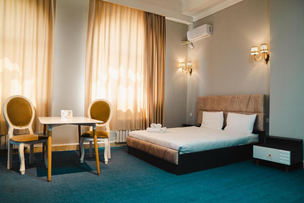 a hotel room with a bed and a table and chairs at Olive Garden Baku Hotel in Baku
